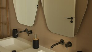 Een badkamer met een lange witte wastafel, twee spiegels en een deur.