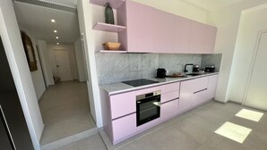 Een moderne keuken met roze kastjes, een zwarte oven en een marmeren aanrecht.