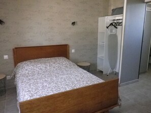 Une chambre avec un lit en bois, une armoire blanche et une petite table ronde.