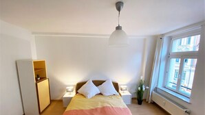Una camera da letto con un letto, lampade sui comodini, una finestra e un termosifone.
