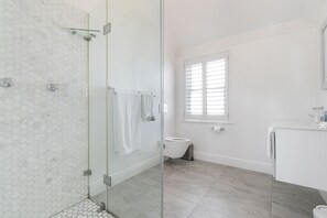 A modern bathroom with a glass shower enclosure, a toilet, and a sink.