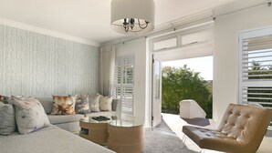 A modern living room with a grey sofa, a leather armchair, and a glass coffee table. - Winelands Golf Lodges 3 (Stellenbosch)