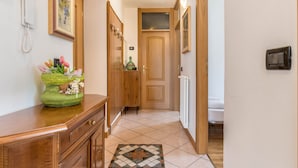 Käytävä, jossa on puinen ovi, patteri, puhelin ja maljakko, jossa on kukkia.