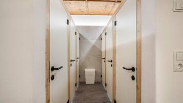 A narrow hallway with wooden doors and a white trash bin.