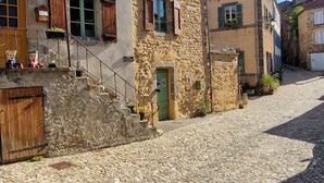 Une rue pavée bordée d’immeubles aux façades en pierre et aux volets en bois.