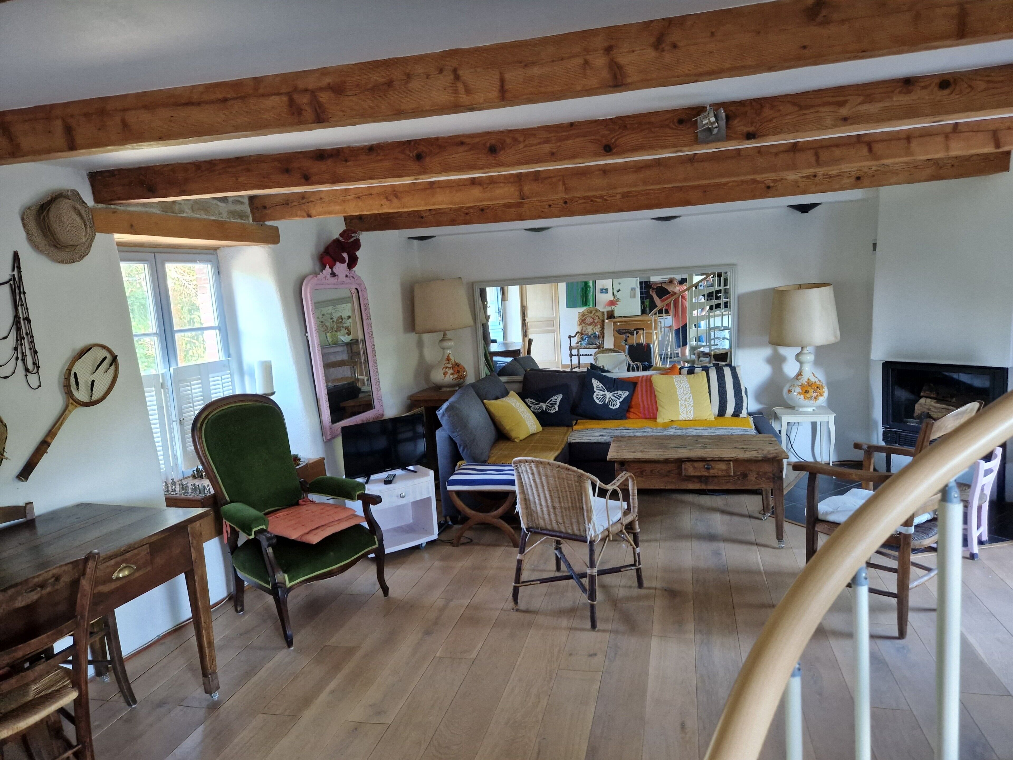 Un salon chaleureux avec un plafond en bois, un ensemble de canapés, une table à manger et un téléviseur.