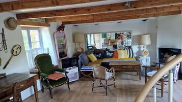Un salon chaleureux avec un plafond en bois, un ensemble de canapés, une table à manger et un téléviseur.