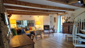 Un salon chaleureux avec un plancher en bois, une cheminée, une table à manger et un escalier.