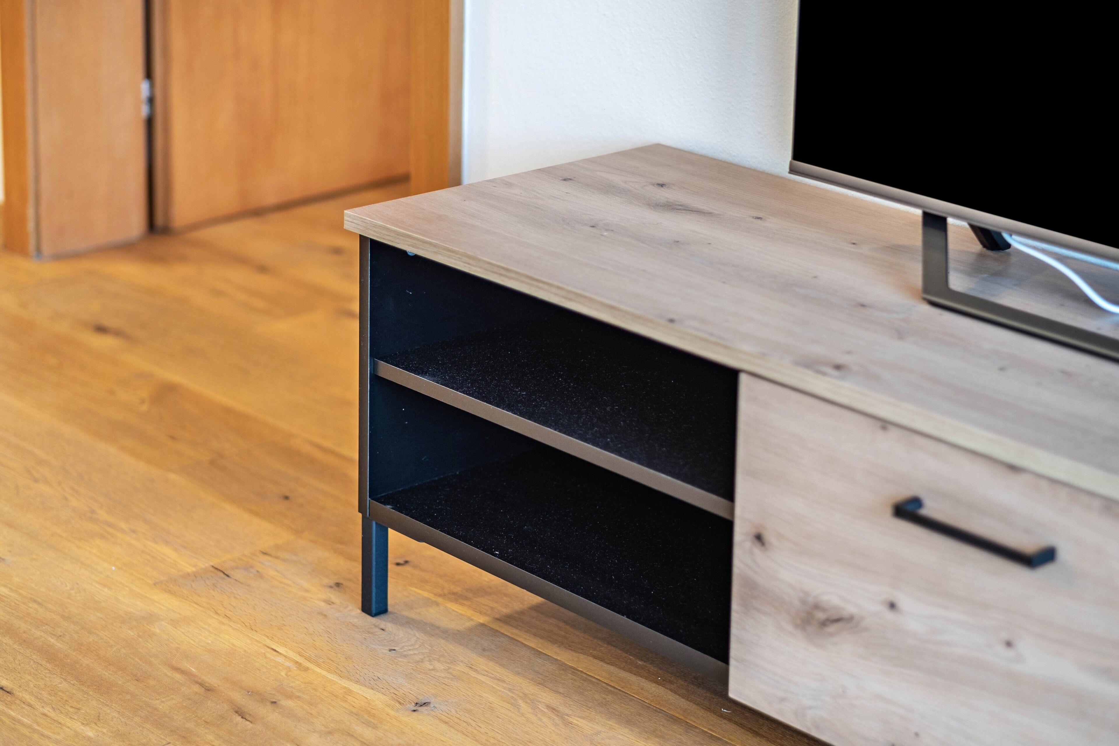 A wooden cabinet with a TV on top, a drawer, and a shelf.