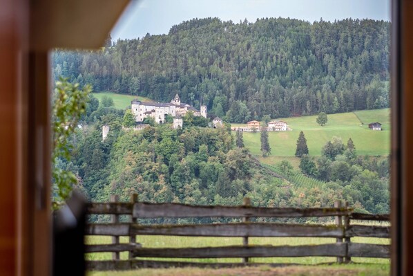 A view of a castle-like building surrounded by lush greenery and hills.