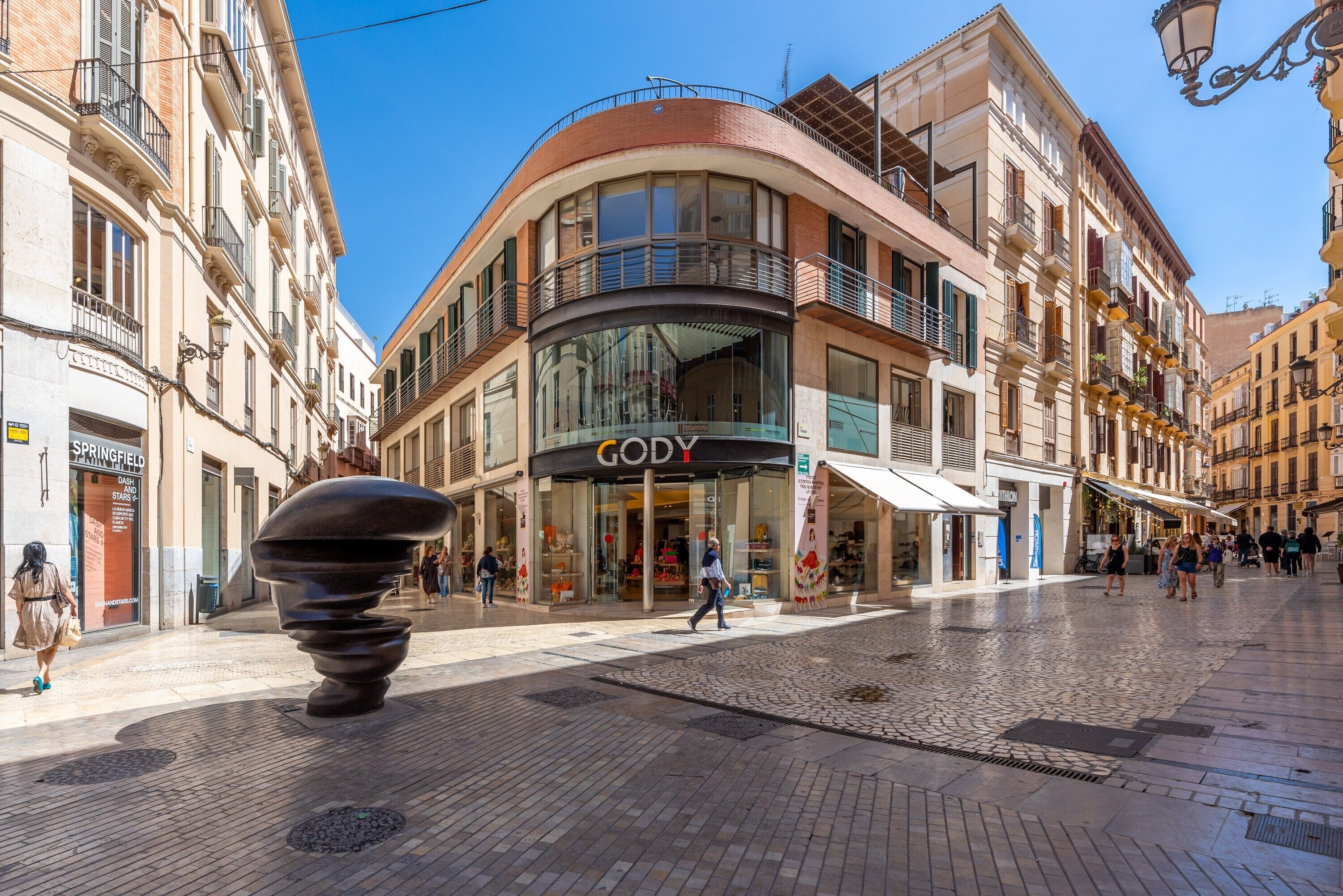 A street with a curved building featuring a store named 'GODY.'