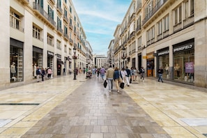 Una calle peatonal bordeada de edificios de varios pisos, algunos con locales comerciales.