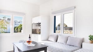 Ein modernes, gut beleuchtetes Zimmer mit Esstisch, einer Couch und einer Küchenzeile.