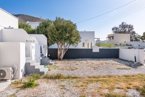 Un bâtiment moderne aux murs blancs, avec un arbre et une cour intérieure recouverte de gravier.