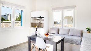 Eine moderne Küche mit Essbereich, einer Couch und Blick ins Freie.