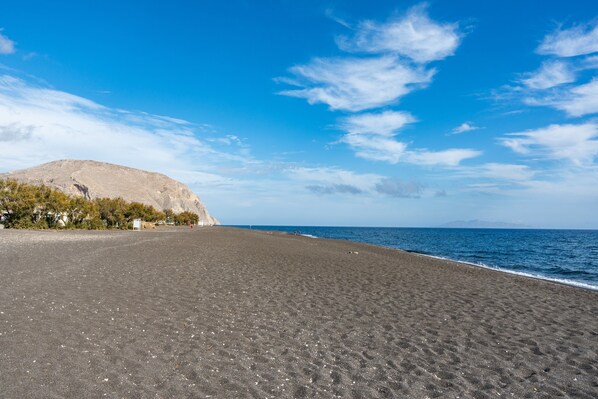 Une plage avec une montagne en arrière-plan, un ciel dégagé et une mer calme.