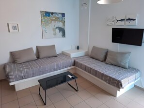 Un salon moderne comprenant deux canapés, une table basse, un téléviseur à écran plat et une œuvre d’art accrochée au mur.