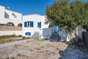 Un bâtiment blanc avec des volets bleus et un arbre devant.