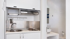 Eine kleine Küchenzeile mit Spüle aus Edelstahl, Gasherd, Backofen und einer Arbeitsplatte.