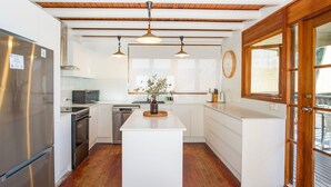 Une cuisine moderne avec des meubles blancs, des appareils en acier inoxydable et un plancher en bois.