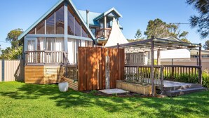 Une maison moderne dotée d’une grande terrasse, d’un espace extérieur couvert et d’une pelouse bien entretenue.
