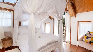 Une chambre à coucher avec un lit à baldaquin, un plancher en bois et une vue sur l’extérieur.