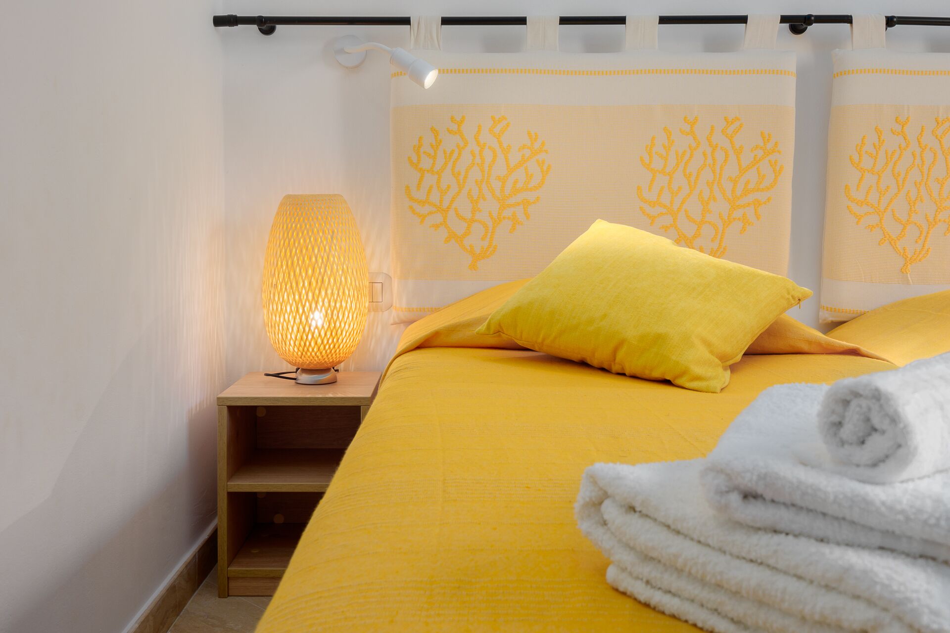 Ein Hotelzimmer mit Bett, Nachttisch, Lampe und Handtuch.