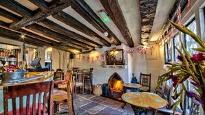 A rustic pub interior with exposed wooden beams, a fireplace, and traditional decor. - The WoolPack Inn (Colchester)