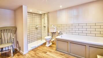 A modern bathroom with a wooden floor, a shower enclosure, a toilet, and a bathtub.