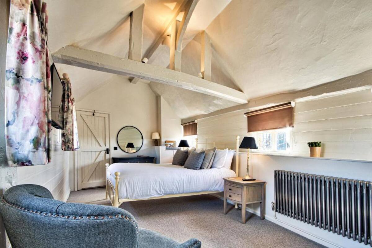 Une chambre avec un lit en mezzanine, une table de chevet, une lampe, un radiateur et une fenêtre donnant sur un beau paysage.