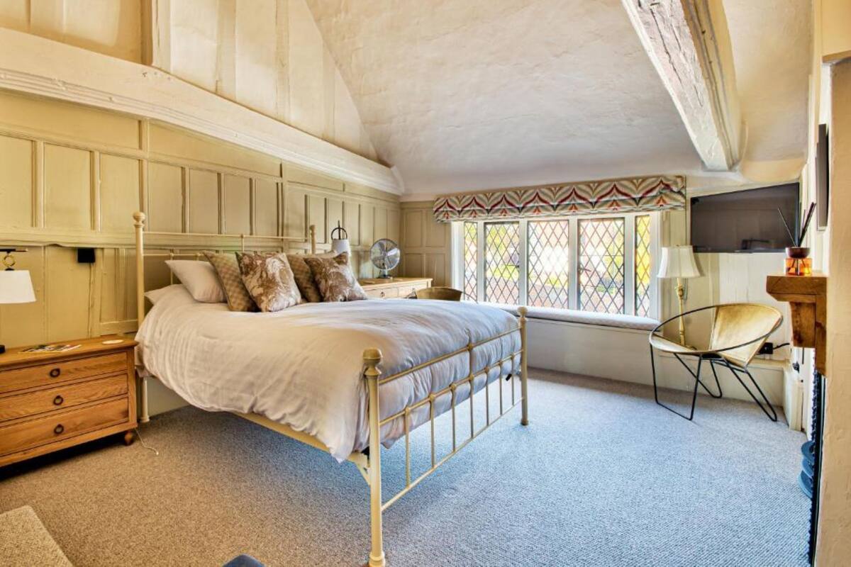 Une chambre à coucher comprenant un lit, une table de chevet, une lampe, une chaise et une fenêtre donnant sur un beau paysage.