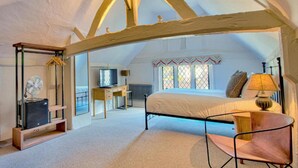 A bedroom with a bed, a chair, a desk with a computer, and a television. - The WoolPack Inn (Colchester)