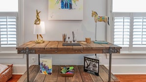 Una mesa de madera con estructura metálica, una lámpara y libros.
