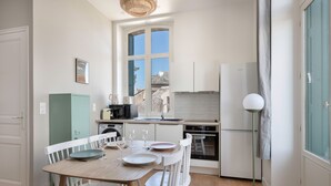 A compact kitchen with a dining table set for four, a view through a window, and a modern floor lamp. - Seaview in the heart of le Croisic (Le Croisic)