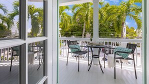 A covered outdoor area with a white railing, a table, and four chairs. - HONEY~ Adult Only, 2nd Floor 1 King Bedroom Unit w/ Community Pool! (Key West)