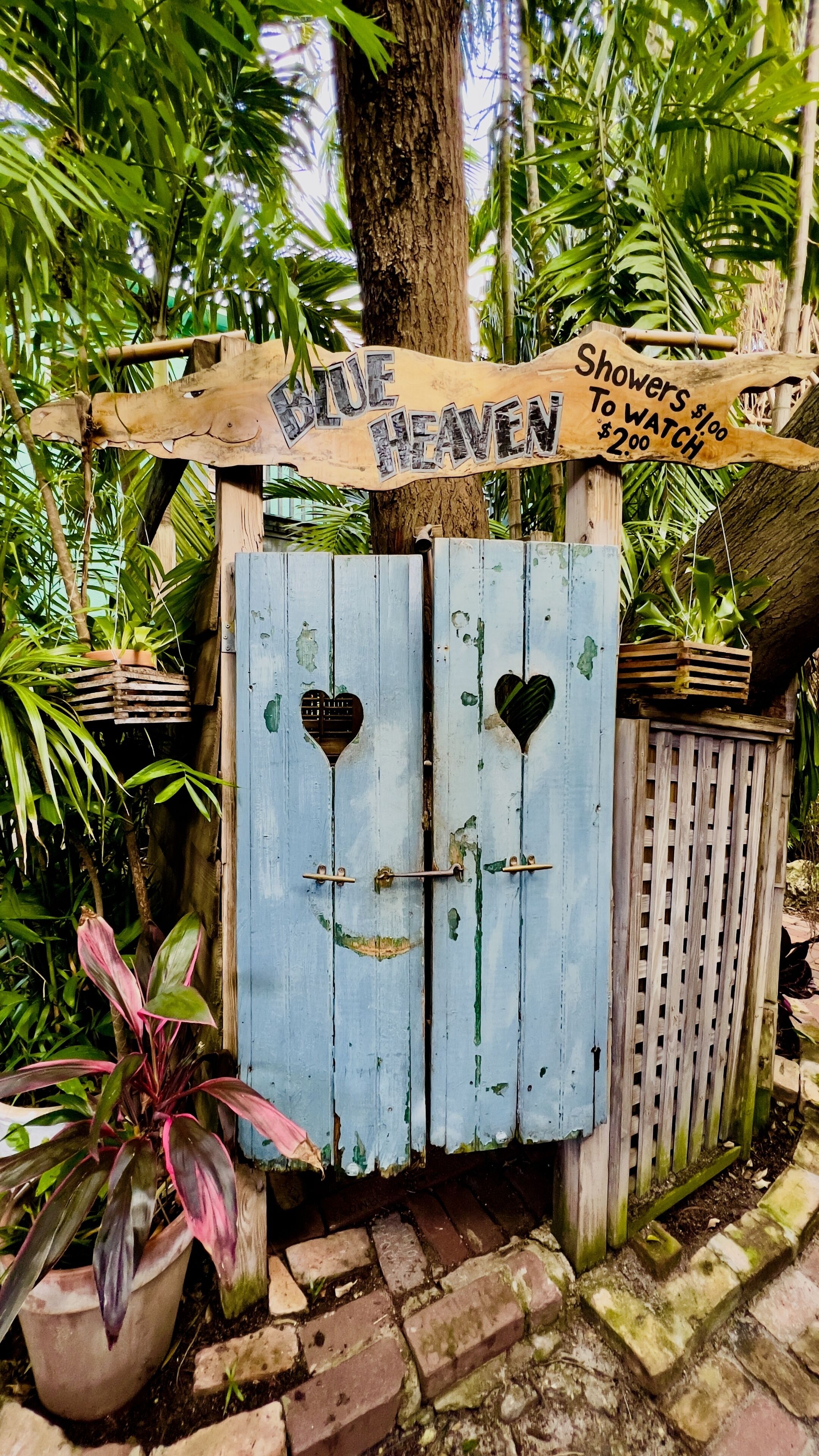 A rustic wooden gate with a sign that reads 'BLUE HEAVEN Showers & Watch $2.00'.