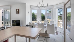 Eine moderne Küche mit Essbereich, großen Fenstern und einer Chandelüster.