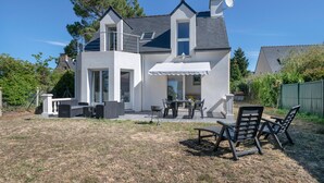 Ein modernes, zweistöckiges Haus mit Terrasse, Sitzgelegenheiten im Freien und einer Satellitenschüssel.