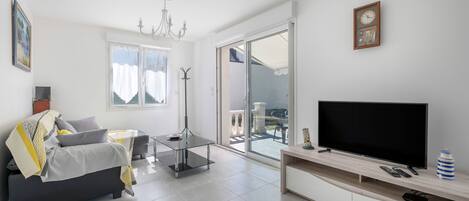A modern living room with a sofa, a coffee table, a TV, and a sliding glass door leading to an outdoor area.