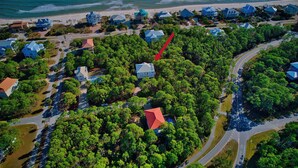 An aerial view of a coastal residential area with houses, roads, and a beach.