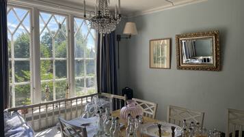 A dining area with a large window, chandelier, and framed pictures on the wall.