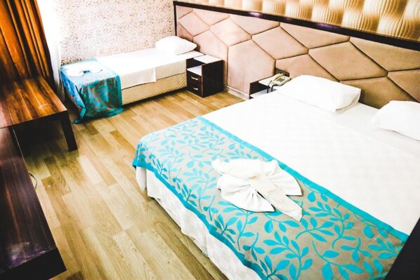 Una habitación de hotel con cama, mesita de noche y un banco de madera.