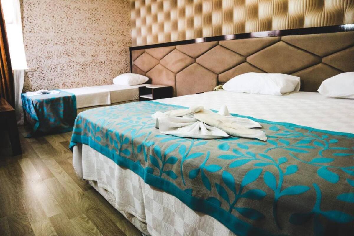 A hotel room with a large bed, a nightstand, and a bedside table.