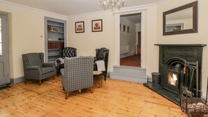 A living room with a fireplace, wooden flooring, and a chandelier. - White Roses (Ross-on-Wye)