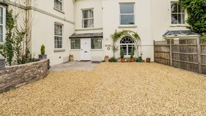 A two-story building with a gravel driveway and a wooden fence. - White Roses (Ross-on-Wye)