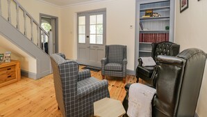 A living room with a staircase, a fireplace, a bookshelf, and a leather armchair. - White Roses (Ross-on-Wye)