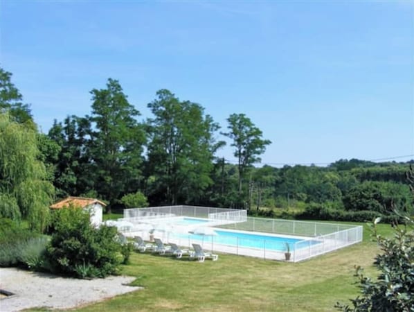 Relax by the pool surrounded by lush greenery and lounge chairs.