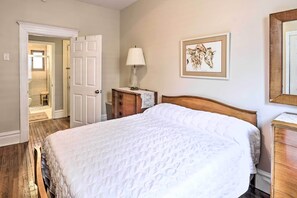 Una camera da letto con un letto grande, un comodino con una lampada, un comò in legno e un quadro appeso al muro.