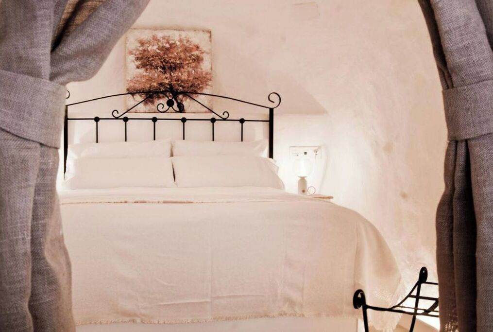 A bed with a metal frame, white bedding, and a wall-mounted artwork above it.
