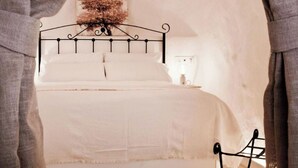 A bed with a metal frame, white bedding, and a wall-mounted artwork above it. - The Monachil Caves: "Lap" (Monachil)